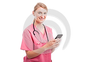Pretty nurse wearing scrubs texting on smartphone