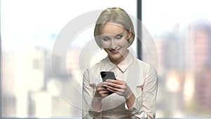 Pretty office woman typing message on her smartphone.