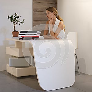 Pretty office worker sitting behind the desk in clear bright room