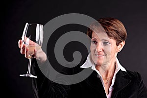 Pretty old woman rising up a glass of wine (focus face)