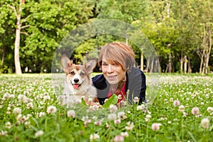 Pretty older woman with corgi dog in summer park