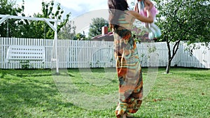 A pretty one-year-old girl in a hat from the sun and a gorgeous dress, goes quietly to her mother. Mom takes baby in her