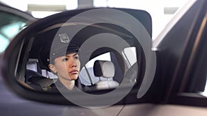 Pretty patrolwoman sitting in car, patrolling and monitoring city law and order