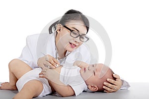 Pretty pediatrician checking a baby on studio