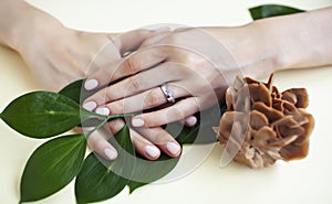 Pretty perfect woman hands with white manicure and green leaf on colorful background with wood, spa cosmetic concept