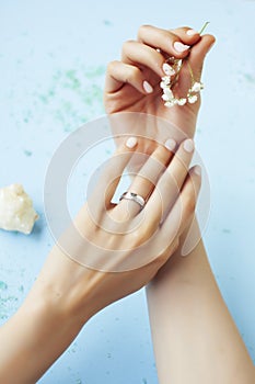 Pretty perfect woman hands with white manicure and little flowers on blue background