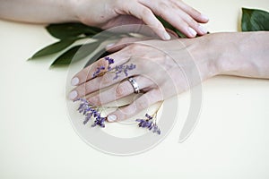 Pretty perfect woman hands with white manicure and little flowers on colorful yellow background, spa concept