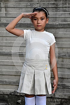 Pretty Philippina Child Saluting Wearing Skirt Near Wall