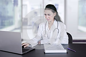 Pretty physician is using a laptop in the clinic