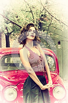 Pretty pin up girl posing on a red retro car background. Playful gaze fixed on camera.