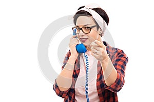 Pretty pin-up girl talking on blue receiver and pointing finger