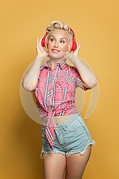 Pretty pin-up woman listening music with headphones and posing