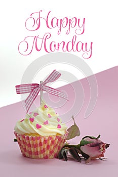 Pretty pink cupcake with pale pink silk rose bud on pink background with Happy Monday sample text