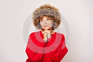 Pretty portrait of curly haired woman wearing red sweeter thinking looking left and smiling a bit, isolated on white