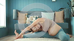 Pretty pregnant mother doing fitness indoors. Expectant mother practicing yoga