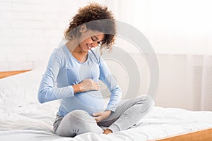Pretty pregnant woman caressing her belly, talking to her baby