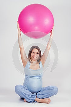 Pretty pregnant woman doing exercise with big gymnastic ball