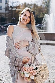 Happy and carefree pregnant woman stand near the fountain