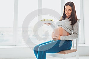 Pretty pregnant woman holding her baby bump