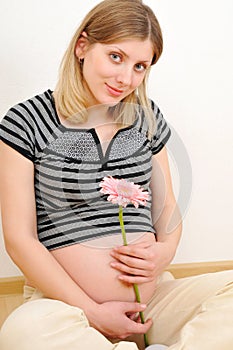 Pretty pregnant woman tenderly holding a flower
