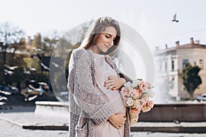 Pretty pregnant woman walking near the fountain