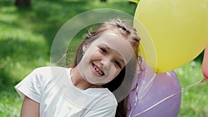 pretty preschool girl having fun playing with hot air balloons outdoors. hollidays, party, birthday, celebration. happy