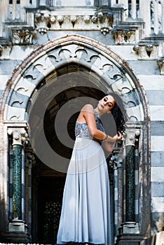 A pretty princess is standing in the entrance of a castle.