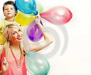 Pretty real family with color balloons on white background, blond woman with little boy at birthday party bright smiling