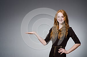 Pretty red hair girl in brown dress against gray