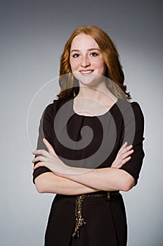 Pretty red hair girl in brown dress against gray