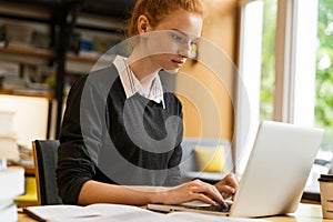 Pretty red haired teenage girl using laptop computer