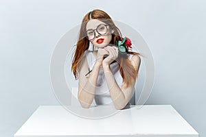 pretty red-haired woman sitting at the table with rose flower in her hands glamor red lips model