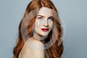 Pretty red haired woman studio portrait. Redhead girl smiling