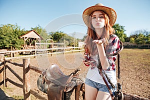 Pretty redhead cowgirl in straw hat sending air kiss