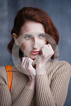 Pretty redhead thin lean young woman with vintage hairdo posing in knit dress. Studio photoshoot.