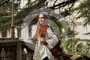Pretty redhead woman in coat in search of beautiful historical place, looking at side