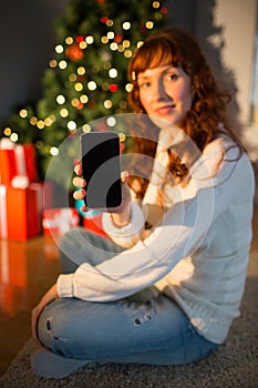Pretty redhead woman showing you mobile phone