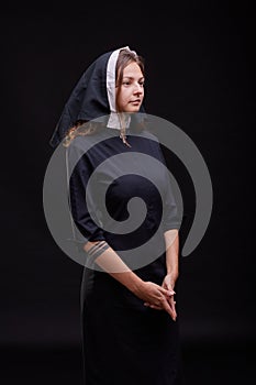 Pretty religious nun in religion concept against dark background.