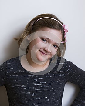 Pretty round-faced smiling little girl with head cocked and cheeky expression