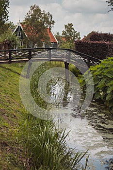 Pretty rural buildings with wooden bridge and trees. Idyllic countryside landscape. Typical holland houses with vintage bridge.