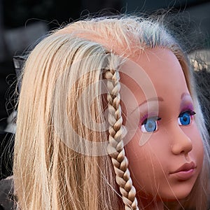 Pretty sad doll with blond hair, blue eyes and a plaited braid