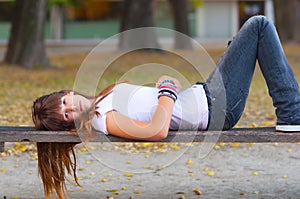 Pretty sad teenage girl lying on the bench