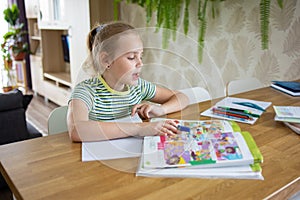 A pretty school-age girl does her homework based on a textbook and records the information in a workbook. The idea of photo