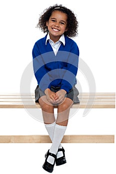 Pretty school girl seated comfortably on a bench