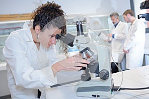 Pretty science student using microscope at university