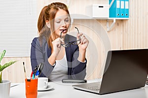 Pretty secretary with glasses in hand working on a computer