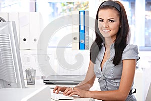 Pretty secretary typing on computer smiling