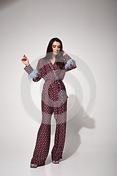 Pretty sexy woman beautiful face natural makeup brunette hair wear silk textile suit pants and blouse with feathers shoes comfort