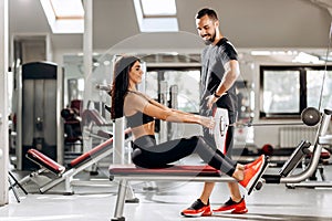 Pretty slim girl is doing exercises for the abdominals on a special exercise machine under the supervision of a coach in
