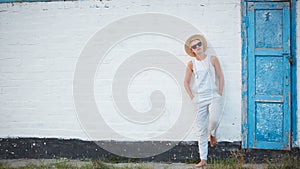 Pretty slim tan blonde stylish woman in straw hat and sunglasses posing